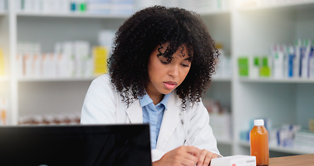 Image showing Young and focused pharmacist use her computer to do stock taking and dispense medicine in a pharmacy or drugstore. Female health professional or chemist filling out prescription medication documents