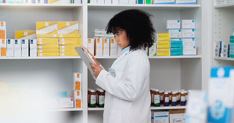 Image showing Young and focused pharmacist use her tablet to do stock taking in a modern pharmacy drugstore. Multiethnic female health professional worker or medication expert in a chemist using a digital gadget