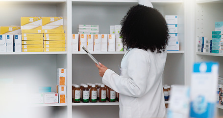 Image showing Young and focused pharmacist use her tablet to do stock taking in a modern pharmacy drugstore. Multiethnic female health professional worker or medication expert in a chemist using a digital gadget