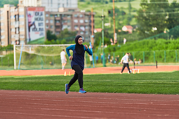 Image showing A muslim woman in a burqa sports muslim clothes running on a marathon course and preparing for upcoming competitions