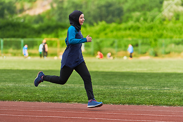 Image showing A muslim woman in a burqa sports muslim clothes running on a marathon course and preparing for upcoming competitions