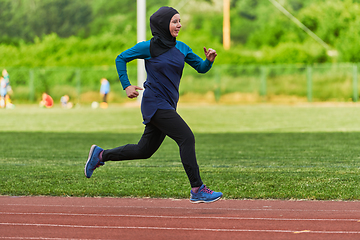 Image showing A muslim woman in a burqa sports muslim clothes running on a marathon course and preparing for upcoming competitions