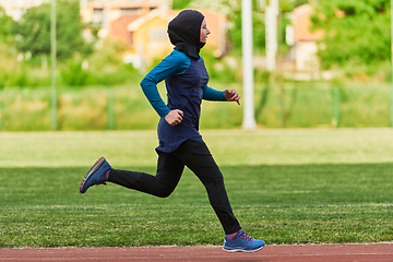 Image showing A muslim woman in a burqa sports muslim clothes running on a marathon course and preparing for upcoming competitions