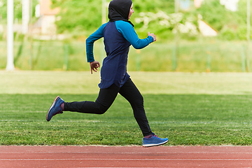 Image showing A muslim woman in a burqa sports muslim clothes running on a marathon course and preparing for upcoming competitions