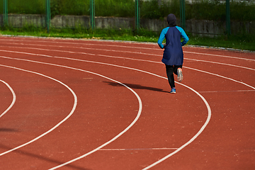 Image showing A muslim woman in a burqa sports muslim clothes running on a marathon course and preparing for upcoming competitions