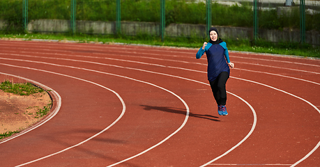 Image showing A muslim woman in a burqa sports muslim clothes running on a marathon course and preparing for upcoming competitions