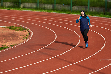 Image showing A muslim woman in a burqa sports muslim clothes running on a marathon course and preparing for upcoming competitions