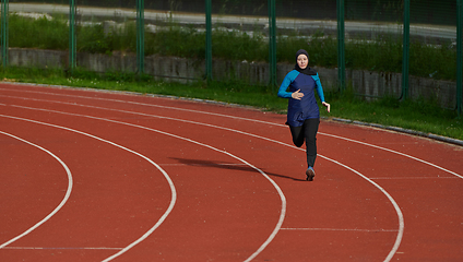 Image showing A muslim woman in a burqa sports muslim clothes running on a marathon course and preparing for upcoming competitions