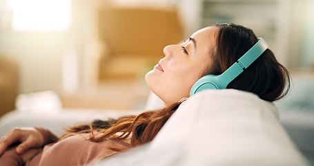 Image showing Relax, headphones and happy woman listening to music, radio or podcast while resting on sofa. Happiness, smile and calm girl from singapore sitting on the couch in living room at home with technology