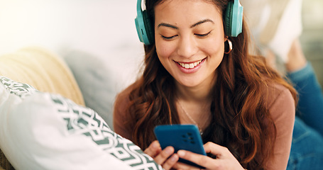 Image showing Girl, phone and music on sofa to relax with headphones with smile, typing and happy on social media. Woman, smartphone and streaming song on internet while reading communication, blog post or email