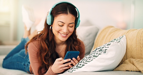 Image showing Girl, phone and music on sofa to relax with headphones with smile, typing and happy on social media. Woman, smartphone and streaming song on internet while reading communication, blog post or email