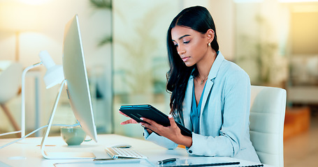 Image showing Businesswoman typing out financial reports while working on a tablet in her office. Female accountant managing finances and doing bookkeeping using software to compile data and writing notes