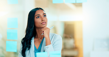 Image showing Serious business woman brainstorm project ideas at a board with colorful sticky notes. Female marketing manager standing and writing business plan. Office worker thinking about corporate strategy.