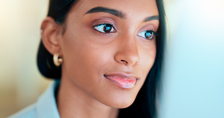 Image showing Business woman reading information on a computer screen while working in an office. Closeup on face of one confident young entrepreneur and focused expert carefully analyzing ideas and plans online