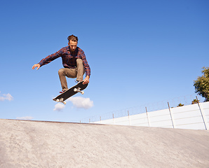 Image showing Perfecting his tricks. A young man doing tricks on his skateboard at the skate park.