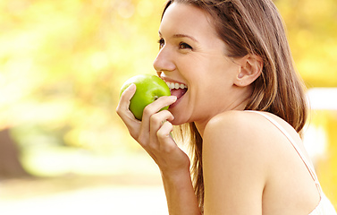 Image showing Its more than just an apple.... Shot of an attractive young woman in the park on an autumn day.