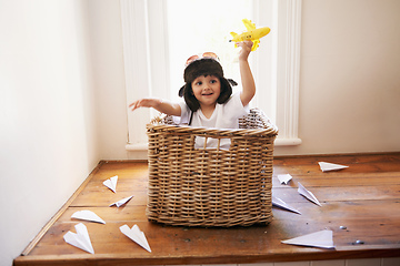 Image showing Let your imagination take flight. A little boy playing with toy airplanes while sitting in a basket.