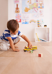 Image showing The wheels on the bus go round and round. Shot of a cute little boy playing with his toys in his room.