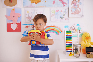 Image showing No sharing. A young boy possessively clasping his toy truck to his chest.