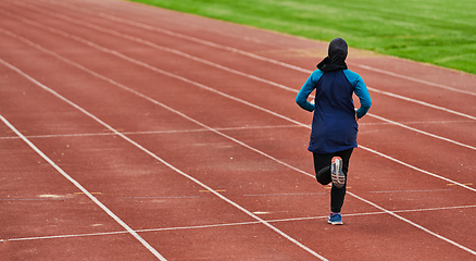 Image showing A muslim woman in a burqa sports muslim clothes running on a marathon course and preparing for upcoming competitions