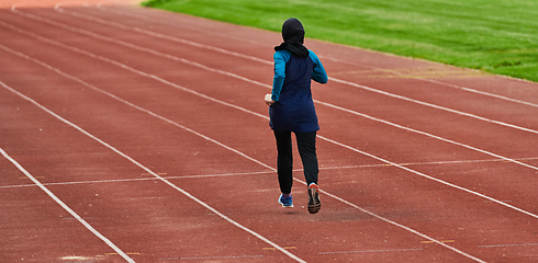 Image showing A muslim woman in a burqa sports muslim clothes running on a marathon course and preparing for upcoming competitions