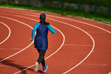 Image showing A muslim woman in a burqa sports muslim clothes running on a marathon course and preparing for upcoming competitions