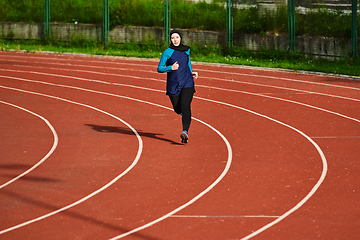 Image showing A muslim woman in a burqa sports muslim clothes running on a marathon course and preparing for upcoming competitions