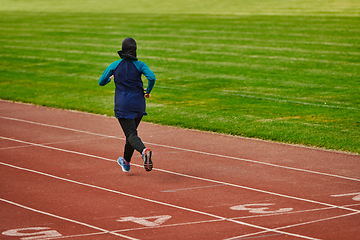 Image showing A muslim woman in a burqa sports muslim clothes running on a marathon course and preparing for upcoming competitions