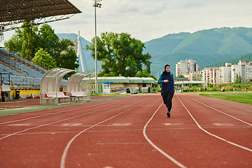 Image showing A muslim woman in a burqa sports muslim clothes running on a marathon course and preparing for upcoming competitions