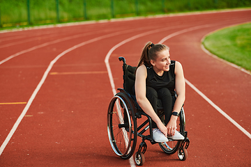 Image showing A smiling woman with disablitiy sitting in a wheelchair and resting on the marathon track after training