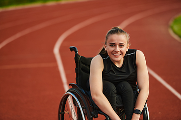 Image showing A smiling woman with disablitiy sitting in a wheelchair and resting on the marathon track after training