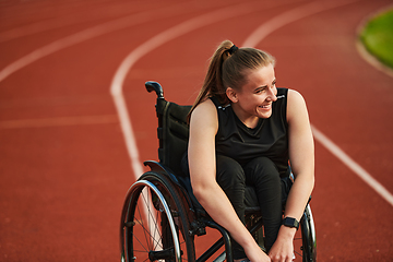 Image showing A smiling woman with disablitiy sitting in a wheelchair and resting on the marathon track after training