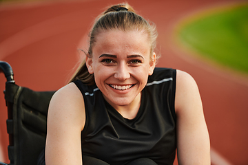 Image showing A smiling woman with disablitiy sitting in a wheelchair and resting on the marathon track after training