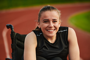 Image showing A smiling woman with disablitiy sitting in a wheelchair and resting on the marathon track after training