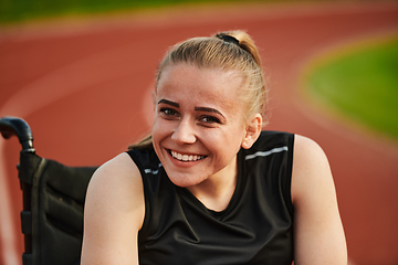 Image showing A smiling woman with disablitiy sitting in a wheelchair and resting on the marathon track after training