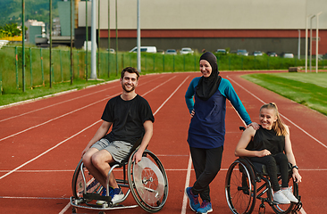 Image showing A woman with a disability in a wheelchair talking after training with a woman wearing a hijab and a man in a wheelchair