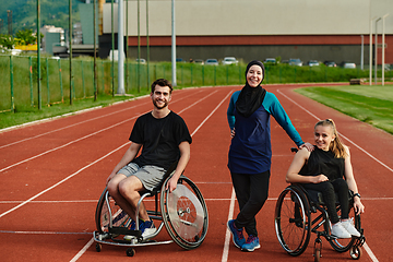 Image showing A woman with a disability in a wheelchair talking after training with a woman wearing a hijab and a man in a wheelchair