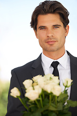 Image showing A peace offering. Portrait of a handsome young man wearing a suit and holding a bunch of roses.