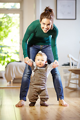 Image showing Hes learning so fast. Smiling young mom helping her baby boy learn to walk.