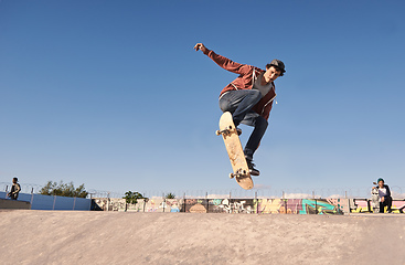 Image showing Getting some air. A young man doing tricks on his skateboard at the skate park.