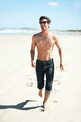 Image showing Fun in the sun. An attractive young man walking on the beach.