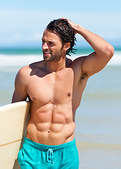 Image showing Surfing keeps him in great shape. An attractive young man heading to the water with his surfboard.