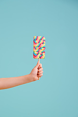 Image showing Have a taste..its delicious. A little girls hand holding a hard candy lollipop.