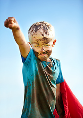 Image showing A muddy superhero. A little boy dressed as a superhero and covered in mud.