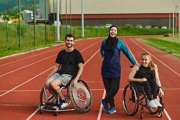 Image showing A woman with a disability in a wheelchair talking after training with a woman wearing a hijab and a man in a wheelchair