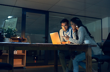 Image showing Making important decisions together to improve their chances at success. Cropped shot of two colleagues working late on a laptop in an office.