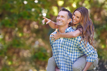 Image showing Look over there. A handsome man giving his wife a piggyback outdoors.