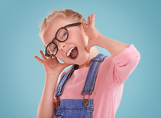 Image showing These glasses make me feel cute. Studio shot of a little girl wearing hipster glasses on a blue background.