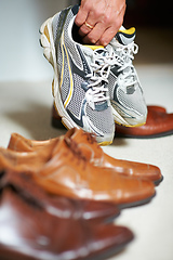 Image showing Shoes for every occasion. Cropped shot of a man grabbing his running shoes from amongst his formal shoes.