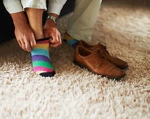 Image showing Adding a little bit of fun to the outfit. Cropped shot of a man putting on colourful socks and loafers.